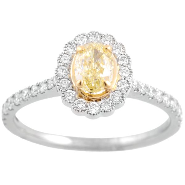 A platinum diamond cluster ring. The central oval fancy yellow diamond is surrounded by round brilliant cut diamonds with further round brilliant cut diamonds to each shoulder.