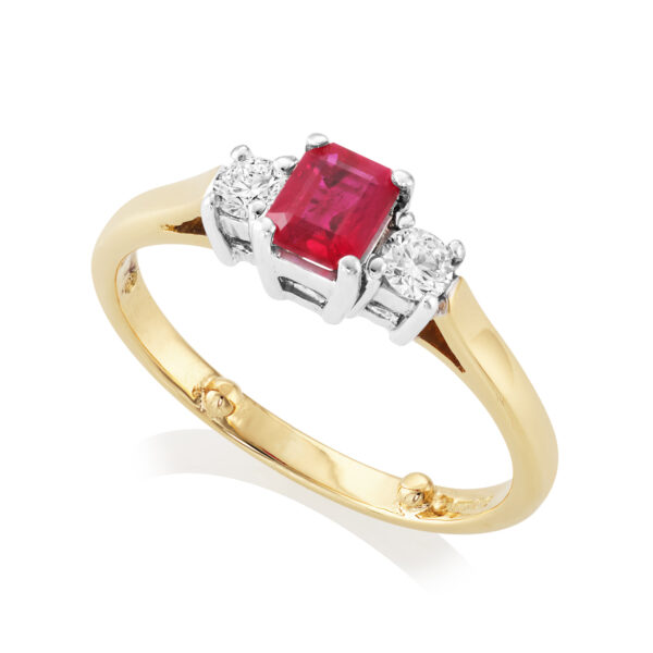 An 18ct yellow and white gold emerald cut ruby and brilliant cut diamond three stone ring. Hallmarked London 2007.