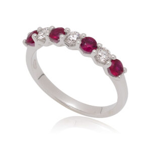 A platinum ruby and round brilliant cut diamond half eternity ring in a V-collet setting, containing seven stones.