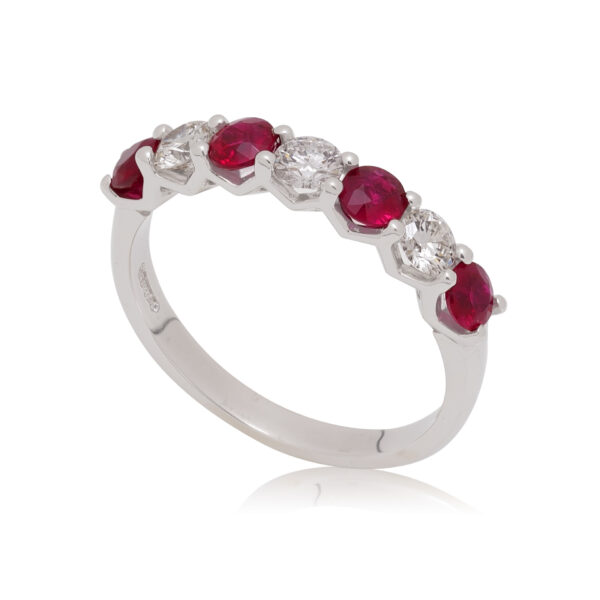 A platinum round brilliant cut ruby and diamond seven stone half eternity ring, with a claw setting.