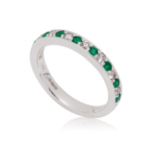 An 18ct white gold emerald and diamond seventeen stone half eternity ring.